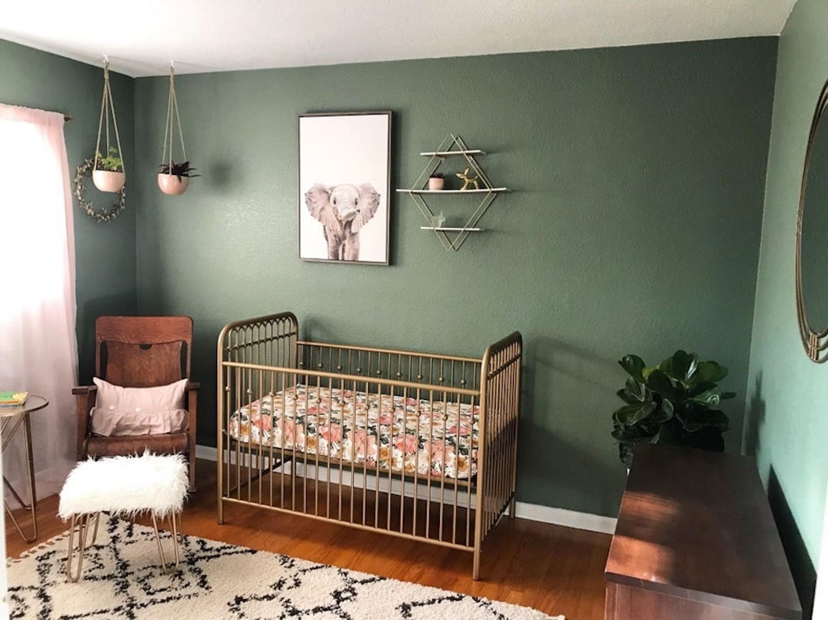 chambre bebe au style retro avec murs peints en vert fonce et lit à barreaux en cuivre et mobilier en bois fonce